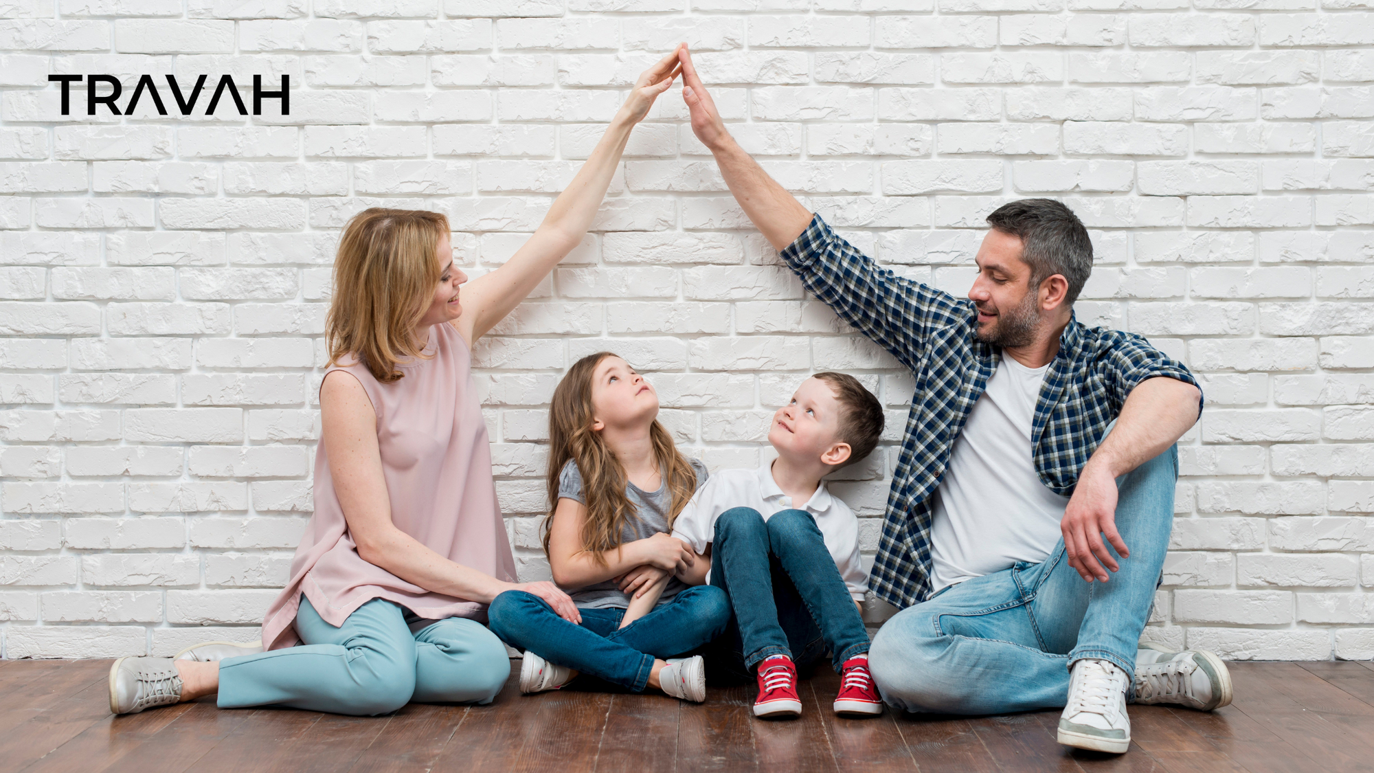 family sitting against wall making the shape of house with arms